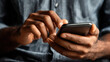 © Som.Ying - Close-up of hands using smartphone with dark skin tone in indoor lighting, showcasing focused interaction with mobile device in casual setting, modern technology engagement.