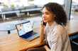 © Yaroslav Astakhov - A determined woman makes an important call while efficiently working on her laptop in a stylish cafe