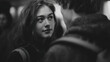 © Som.Ying - Young woman gazing intently at another person in a black and white setting, showcasing deep emotions in a crowded environment with soft lighting and intimate atmosphere.