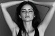 © kong - Black and white close-up portrait of a confident young woman with long dark hair, arms raised above head, and a calm, self-assured expression