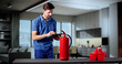 © Andrey Popov - Man In Room Examining Fire Extinguisher For Prevention