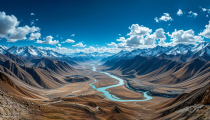Wall Mural - A breathtaking panorama of towering mountains, a turquoise river, and fluffy clouds create a stunning natural vista.