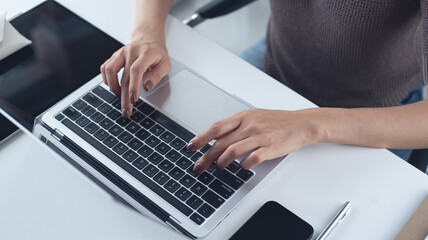 Wall Mural - Close up of business woman hands working, typing on laptop computer keyboard, surfing the internet on office desk, online working, telecommuting, freelance at work concept