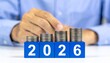 © photostockatinat - The growing financial success with a stack of coins and the year 2026 in the image