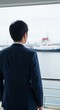 © LYKASTOCK - Businessman Gazing at Harbor with Ferry