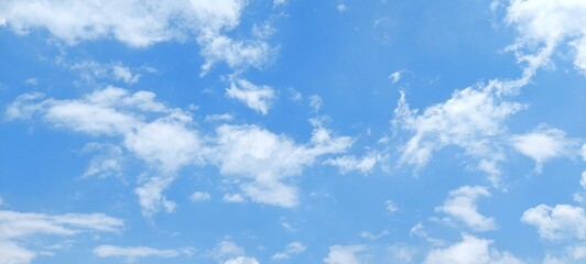 Wall Mural - Bright blue sky with soft white clouds on a sunny day. Blue sky with scattered clouds. Clear blue sky, bright spring, wallpaper landscape, aerial view. Natural sky background.