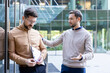© Liubomir - Two male colleagues standing outside an office building, one comforting the other who is looking down and holding documents, possibly after experiencing job stress or a difficult conversation