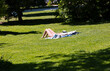 Blonde woman sunbathing on the grass wearing a white bikini - El Retiro park, Madrid, Spain