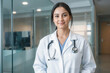 © Sync - Femal woman doctor smiling in white lab coat uniform with stethoscope standing in a modern medical hospital clinic for hospitality and wellness in healthcare industry