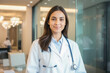 © Sync - Femal woman doctor smiling in white lab coat uniform with stethoscope standing in a modern medical hospital clinic for hospitality and wellness in healthcare industry