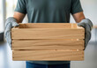 © Aurora Aesthetics - A volunteer in work gloves holds a large empty wooden crate a concept for donations charity drives and community support with copy space on the side of the box