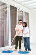 © Freddy Chandra - couples clean a bright modern interior using mops on a glossy white tile floor