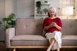 © snowing12 - Happy older Asian woman uses smartphone at home smiling on cozy sofa Senior lady enjoys modern technology and online connection in comfortable living room