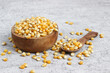 © AhsannCreative - Corn kernels. Raw popcorn in a wooden bowl isolated on a gray background.