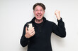 © Ranta Images - Scandinavian mid adult man using phone against white background happy with arm raised