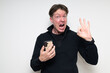 © Ranta Images - Scandinavian mid adult man using phone against white background making OK sign gesture