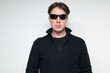 © Ranta Images - Portrait of Scandinavian mid adult man in black sweater wearing sunglasses against white background