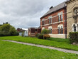 Historic red brick building beside a lush green lawn in Manchester, UK