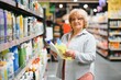 © Serhii - Elderly woman buying household chemicals or laundry detergent at supermarket.