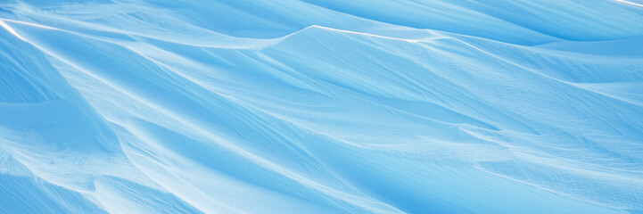 Wall Mural - Snow texture. Wind sculpted patterns on snow surface. Wind in the tundra and in the mountains on the surface of the snow sculpts patterns and ridges. Arctic, Polar region. Winter panoramic background.