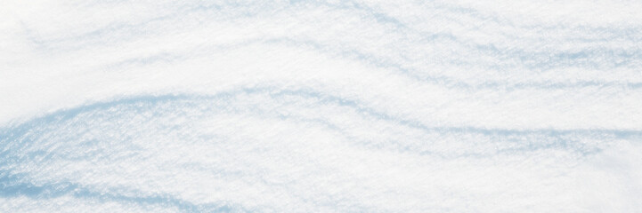 Wall Mural - Wide panoramic winter background with snowy ground. Natural snow texture. Wind sculpted patterns on snow surface.