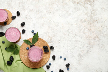 Wall Mural - Glasses of fresh blackberry smoothie and blueberries on white background