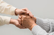 © Pixel-Shot - Woman holding grandmother's hands on light background