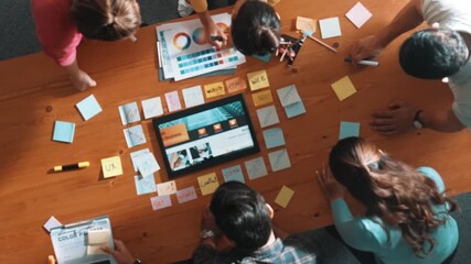 Top view of business people working together to design web design. Aerial view of designer brainstorming and discussing about website interface and looking at tablet with digital design. Symposium.