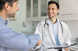 © fizkes - Happy smiling male doctor shake hands with mid aged patient