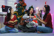 © crizzystudio - Friends celebrating christmas playing guitar eating popcorn