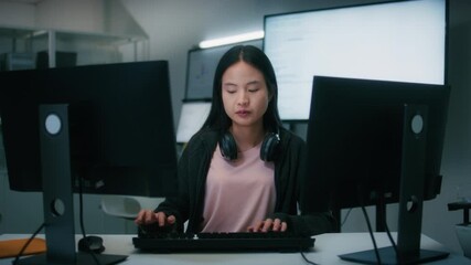 Female Computer Programmer working on Computer Writing and Developing Software Program, App looking at Dual screens in Creative Office workspace. Focused Professional female software developer work.