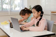 © SHUTTER DIN - Two girls are intently focused on their online class in a classroom or at home,