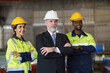 © ronnachaipark - A foreman and worker are standing in a factory, looking standing pose. They wear a yellow and white safety helmet for safety.
