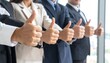 © Orbit - Business professionals in suits giving thumbs-up indoors, symbolizing approval, unity, and positive team morale.