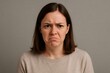 © Татьяна Евдокимова - Caucasian woman expressing frustration and disappointment, showcasing a range of negative emotions against a gray background in a studio setting
