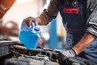© Ілона Kozlovska - Service professional pouring blue liquid from a container into an open car engine at an auto shop