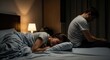 © MMerellinn - Couple conflict in bedroom, wife crying under covers, husband sitting apart on bed with head bowed, relationship problems, emotional distress, separation anxiety, marital issues, feeling alone.