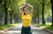© Viktor - Young caucasian woman, yellow shirt, green leggings, stretches arms overhead in park. Smiles, radiating health, happiness during outdoor exercise. Fit female embodies active lifestyle, embracing