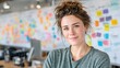 © Rizky - Confident Young Businesswoman with Curly Hair Posing in Office with Whiteboard Covered in Colorful Notes Goals and Strategies in Background