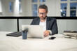 © Volodymyr - Business worker with laptop at office. Employee remote working in modern office. Business man on online meeting. Hispanic business man working online. Mature business man using laptop at workplace.