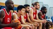 © SAFIICLON - A diverse team of male basketball players in red uniforms sitting focused on the bench during a competitive game