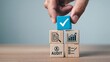 © Pixim Stock - Hand places a blue block with a white checkmark on top of wooden blocks representing business concepts like audit and growth