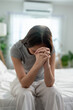 © Kawee - Depressed Asian woman feel upset while sitting alone on bed in bedroom.