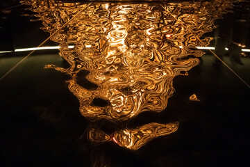 Wall Mural - An abstract pattern of firelight and reflections on a glossy surface, with golden swirls and shimmers. A natural and strange background with a contrasting appearance of a shapeless structure