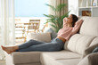 © Antonioguillem - Happy woman is relaxing on comfortable couch at home