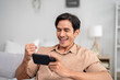 © Kawee - Asian young handsome man gamer play mobile game on smartphone at home.