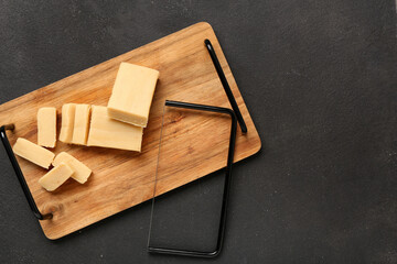 Wall Mural - Wooden board with tasty marzipan and cheese slicer on dark background