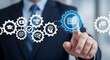 © alvi - A businessman in a suit interacts with a digital interface featuring gears and icons representing education, training, and business processes.