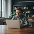 © Arif - A focused professional works diligently on his laptop in a modern office