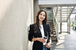 © lijun - Smiling young businesswoman holding a cup of coffee